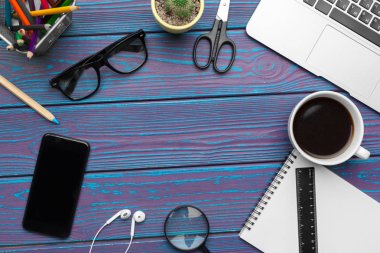 Boş not defteri, dizüstü bilgisayarı ve ofis malzemeleri olan ofis masası.
