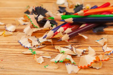 Ahşap arka planda renkli kalemler ve kalem kesimleri yakın