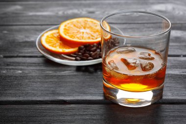 Bir bardak buzlu viski, bir şişe de ahşap çubukta. 