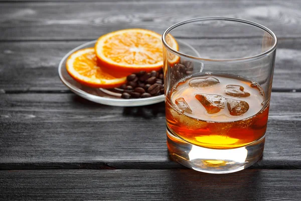 Bir bardak buzlu viski, bir şişe de ahşap çubukta. 