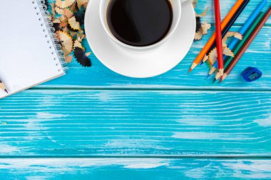 Ahşap arka planda kalem ve kalem kesikli kahve fincanı.