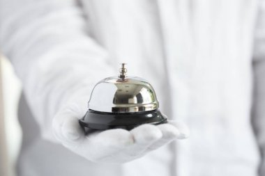 Birinci sınıf hizmet. Otel zilini tutan beyaz eldivenler