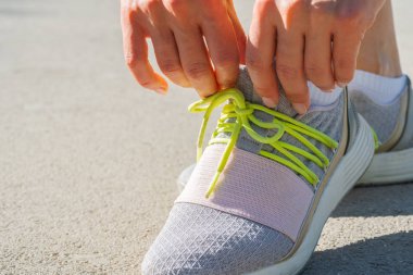 Bir sabah koşusuna hazırlanan ayakkabıbağlarını bağlayan kadın koşucu