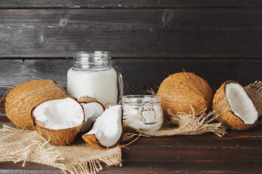 Siyah ahşap arka plan üzerinde kırık hindistan cevizi ve hindistan cevizi sütü