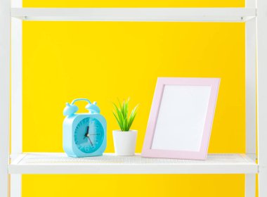 Parlak sarı arka plana karşı kırtasiye nesneleri ile beyaz raf