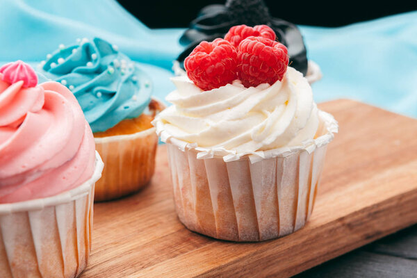 Close up of some decadent gourmet cupcakes frosted with a variety of frosting flavors