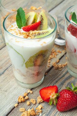 Ahşap masa üstü görünümünde yoğurt, çilek ve granola ile sağlıklı kahvaltı