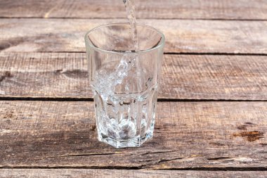 Tahta bir masanın üzerinde bir bardak su..