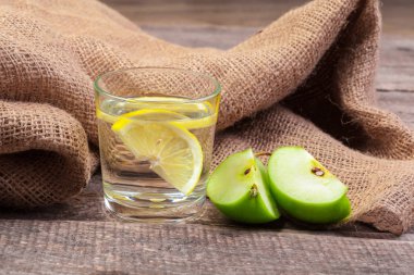 Temiz suda elma dilimleri ve ahşap bir masada taze bir elma ile beslenme içeceği.