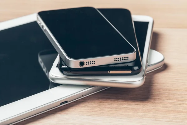 Digital tablet and mobile phone. Electronic devices on wooden table, close up.