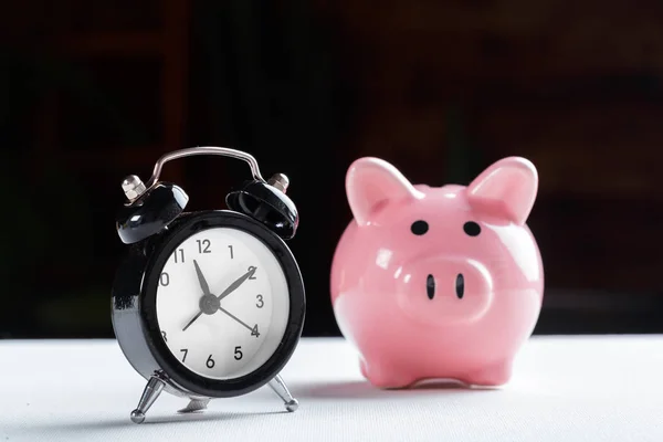 Alarm clock and piggy bank concept for saving time