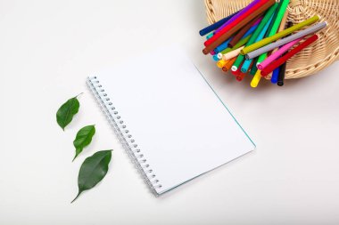 Kağıt ve renkli keçeli kalemler beyaz masada.