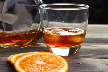 Ahşap arka planda bir şişe viski ve bir bardak viski.