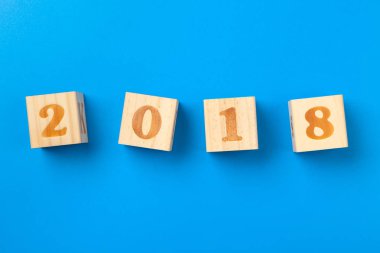 2018 yılı. Mavi arka plan üzerinde ahşap renkli alfabe blokları, düz yatıyordu, üst görünüm. 