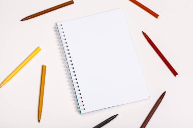 Kağıt ve renkli keçeli kalemler beyaz masada.