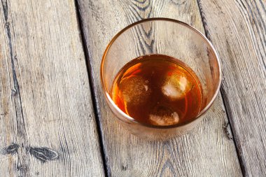 Bir bardak buzlu viski, bir şişe de ahşap çubukta. 