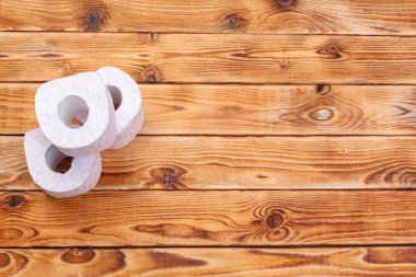 Tuvalet kağıdı ahşap arka plan görünümünde yuvarlanıyor.