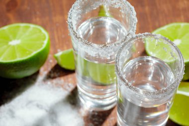 Limon dilimleri ve ahşap tahtada tuz ile tekila.