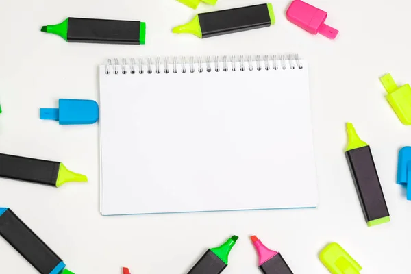 highlighters and  blank notepad paper sheet flat lay on a desk