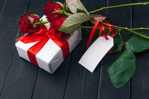 Sevgililer Günü. Kırmızı güller ve hediye kutusu ahşap masada