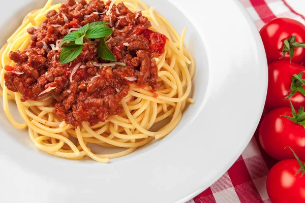 Etli makarna, domates sosu ve sebzeler masada.