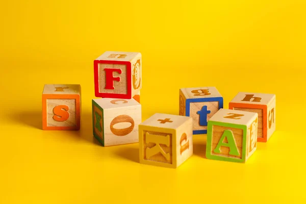 Kleurrijke Houten Blokken Met Letters Een Gele Achtergrond — Stockfoto