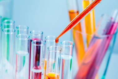 Açık mavi arka plan üzerinde kırmızı ve sarı sıvılar ile laboratuvar test tüpleri