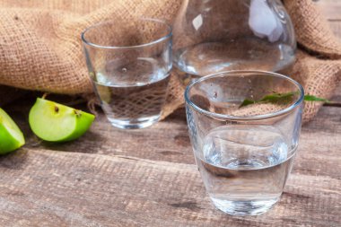 Temiz suda elma dilimleri ve ahşap bir masada taze bir elma ile beslenme içeceği.