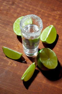 Limon dilimleri ve ahşap tahtada tuz ile tekila.