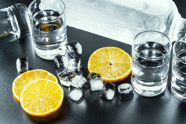 Холодная водка в рюмках на черном фоне.