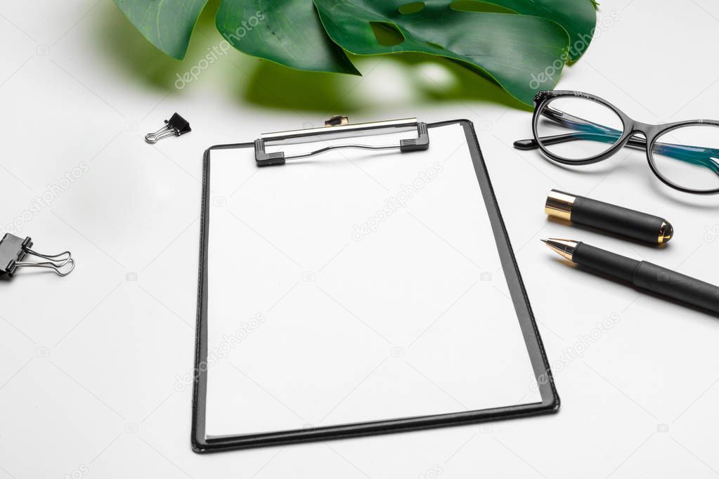 Home office workspace mockup with clipboard, palm leaf and accessories. Flat lay, top view