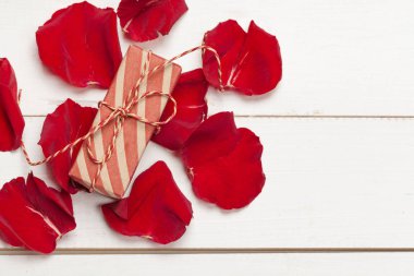 Beyaz arka planda hediye kutusu ve gül yaprağı.