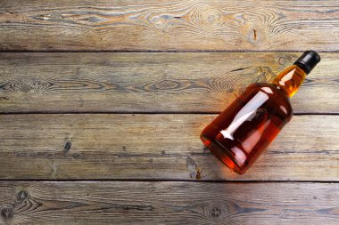 Viski şişesi koyu ahşap arka planda düz yatıyordu.