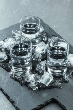 Siyah arka planda shot bardaklarında soğuk votka..