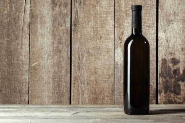 Ahşap arka planda bir şişe şarap.