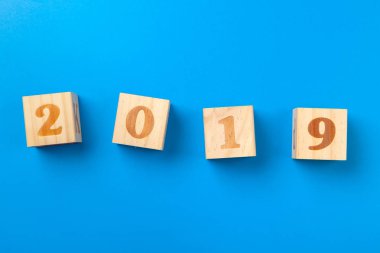 Yıl 2019. Mavi arka plan üzerinde ahşap renkli alfabe blokları, düz yatıyordu, üst görünüm. 