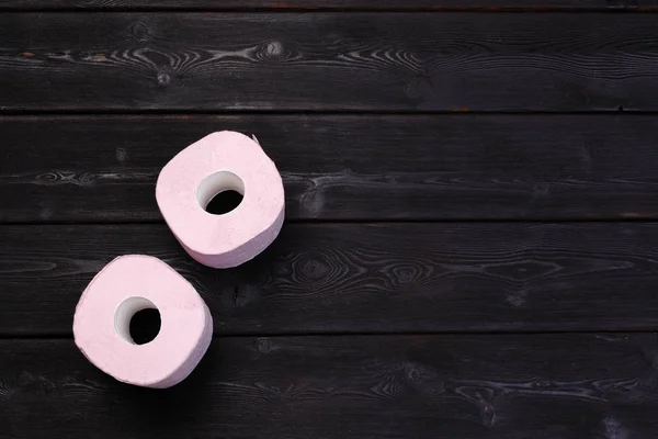黒の木製の背景にパステルピンクのトイレ紙ロール — ストック写真