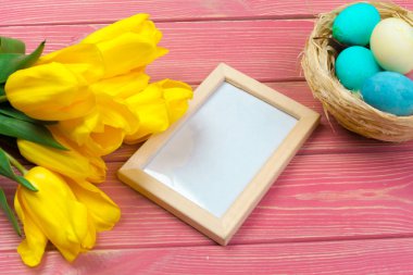 Paskalya konsepti. Renkli arka planda paskalya yumurtaları ve laleleri olan ahşap çerçeve