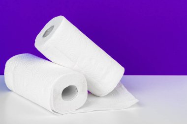 Masanın üzerinde mor arkaplana karşı kağıt havlu rulosu