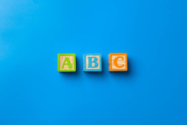 Abc. Mavi arka plan üzerinde ahşap renkli alfabe blokları, düz yatıyordu, üst görünüm. 