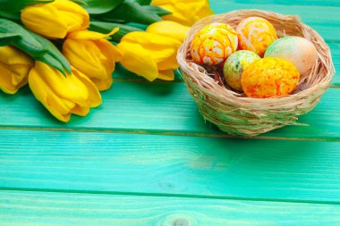Pastel ahşap arka planda süslü yumurta ve çiçeklerle güzel bir Paskalya kompozisyonu. 