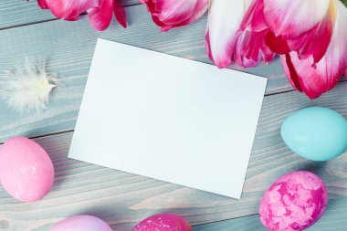 Mavi ahşap arka planda laleleri olan Paskalya yumurtaları