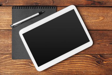 Ahşap arka planda not defteri olan tablet