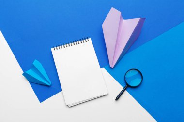 Mavi arka planda ofis malzemeleri olan kağıt uçak. 