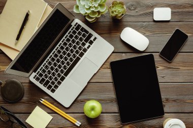 Dizüstü bilgisayar, sarf malzemeleri ve yeşil elma ile Ofis masası, üst görünüm