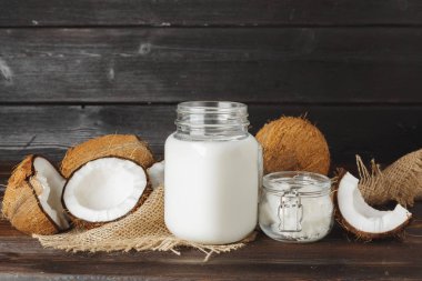 Siyah ahşap arka plan üzerinde kırık hindistan cevizi ve hindistan cevizi sütü