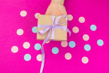 Hediye kutusu pembe bir arka plan üzerinde holding kadın eller