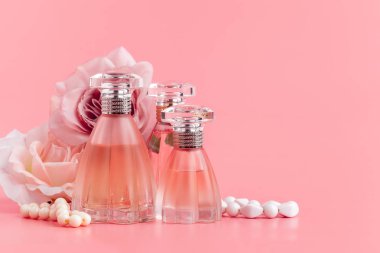 Pembe kumaş arka planında güller olan parfüm şişesi. 