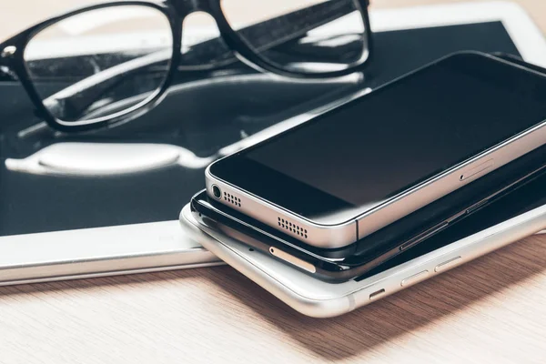 Digital tablet and mobile phone. Electronic devices on wooden table, close up.