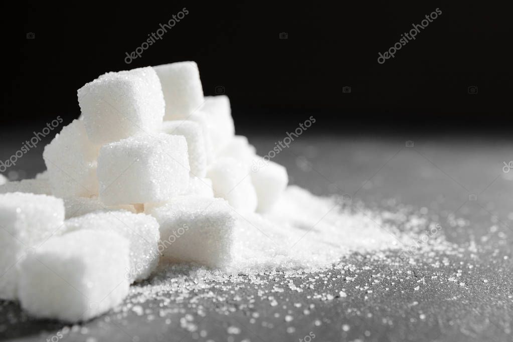 Sugar lumps piled up together against a black background
